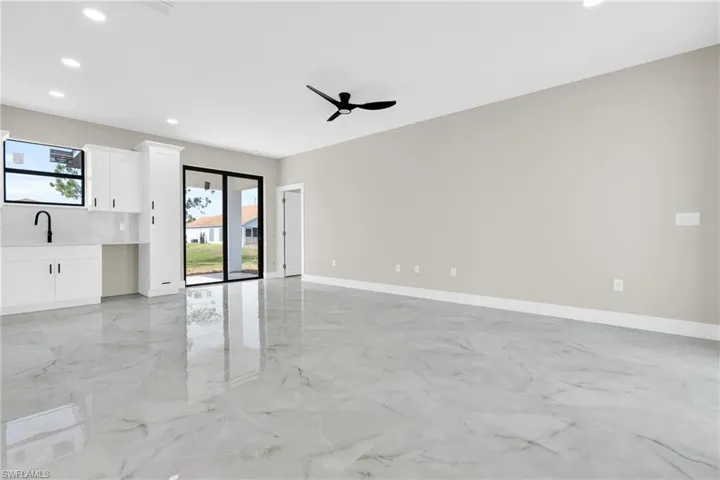 Unfurnished living room with plenty of natural light, recessed lighting, light marble finish flooring, baseboards, and ceiling fan