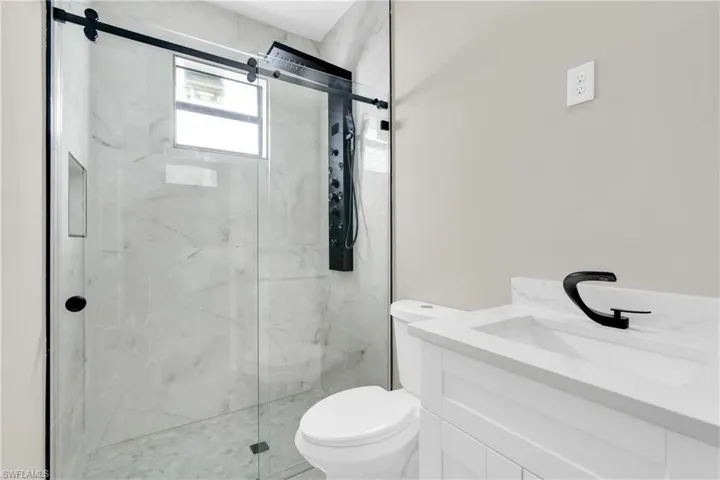 Full bathroom featuring toilet, a marble finish shower, and vanity