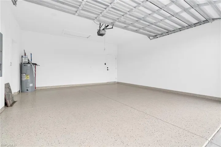 Garage featuring water heater, a garage door opener, and baseboards