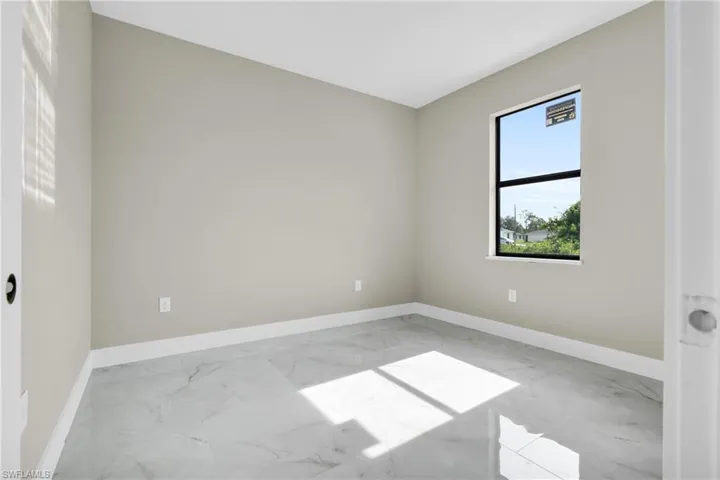 Unfurnished room with marble look tile flooring and baseboards
