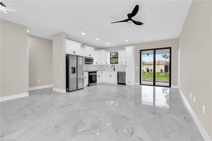 Unfurnished living room featuring light marble finish floors, a ceiling fan, a sink, baseboards, and recessed lighting