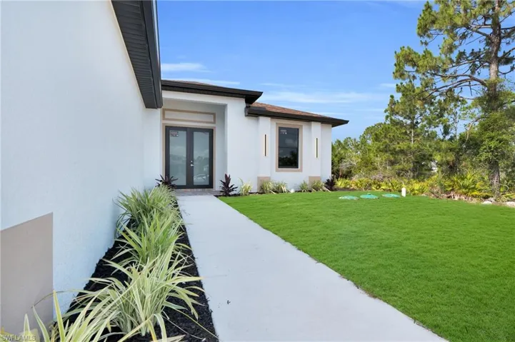 Doorway to property featuring french doors, stucco siding, and a yard