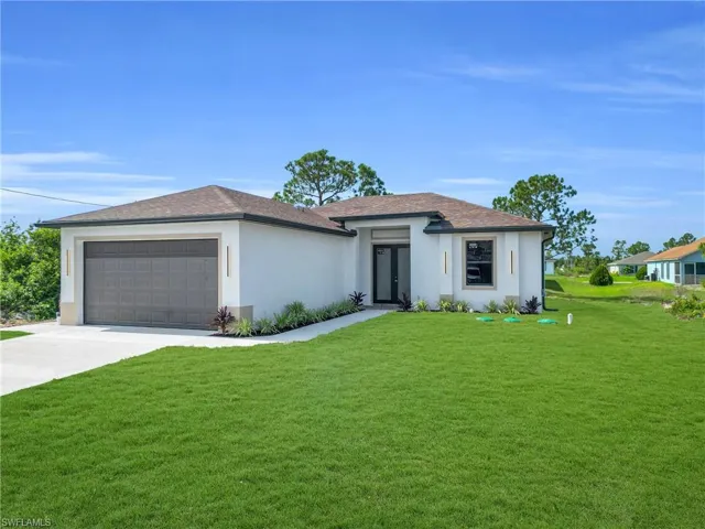 Prairie-style home featuring a garage, stucco siding, a front lawn, driveway, and french doors