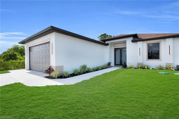 View of front of home featuring a garage, stucco siding, driveway, and a front lawn