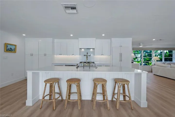 Kitchen with white cabinetry, a spacious island, paneled built in fridge, and light hardwood / wood-style flooring