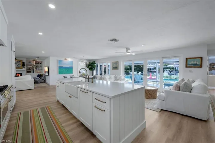 Kitchen featuring a center island with sink, white cabinetry, sink, ceiling fan, and light hardwood / wood-style flooring