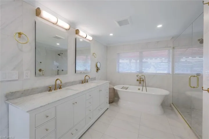 Bathroom featuring vanity, tile walls, tile patterned floors, and separate shower and tub