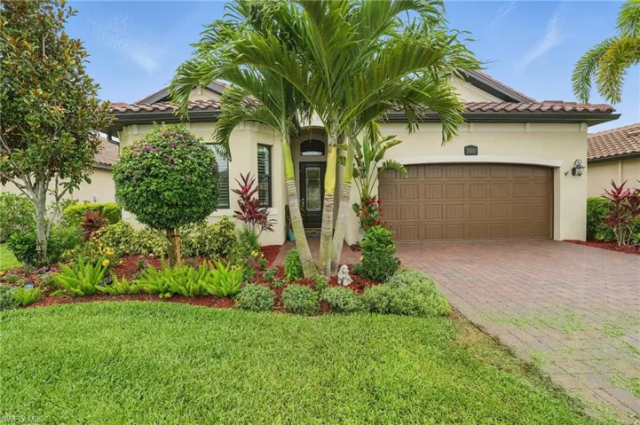 Mediterranean / spanish-style house featuring stucco siding, a garage, decorative driveway, a front yard, and a tile roof