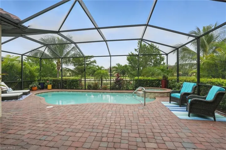 View of swimming pool featuring a patio area, a pool with connected hot tub, and glass enclosure