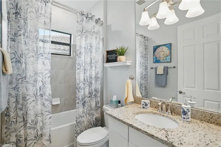 Bathroom with a chandelier, vanity, shower / bath combination with curtain, and toilet