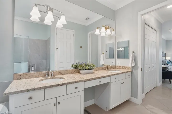 Full bath featuring double vanity, crown molding, and tile patterned floors