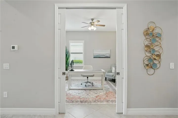 Tiled office with ceiling fan and baseboards