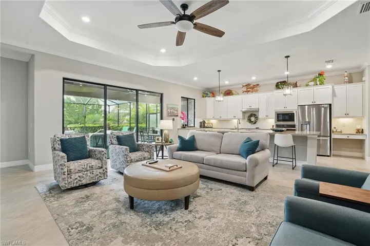 Living area with a tray ceiling, a ceiling fan, crown molding, recessed lighting, and baseboards