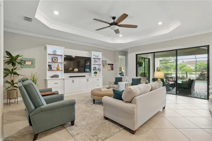 Living area featuring a tray ceiling, ornamental molding, ceiling fan, light tile patterned floors, and recessed lighting
