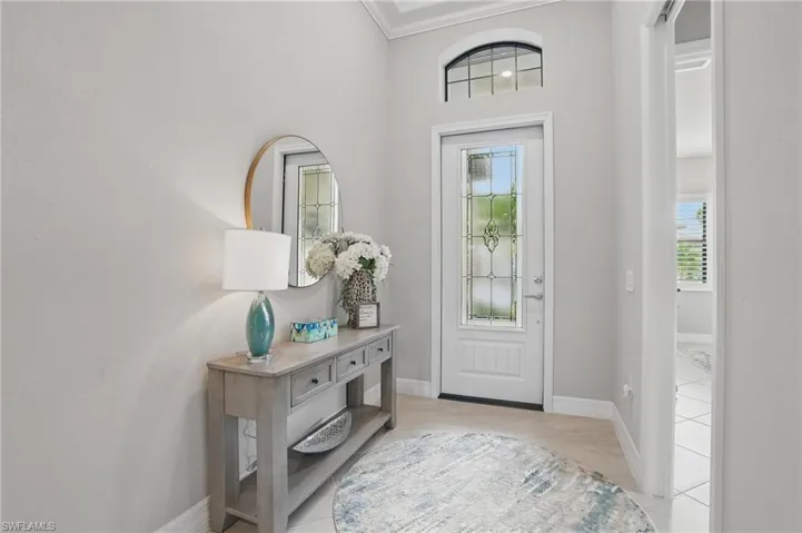 Entryway featuring light tile patterned floors, ornamental molding, and baseboards