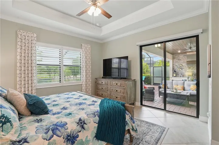 Bedroom with access to outside, crown molding, a raised ceiling, light tile patterned floors, and a ceiling fan