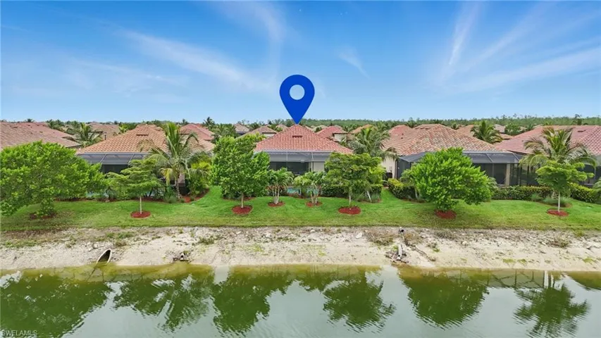 Back of house with a water view, a tile roof, a lanai, a residential view, and a lawn