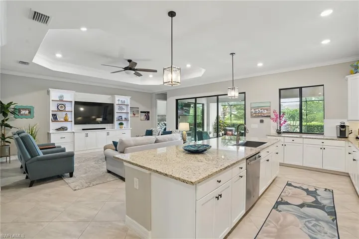 Kitchen with a sink, stainless steel dishwasher, ceiling fan, a kitchen island with sink, and white cabinets
