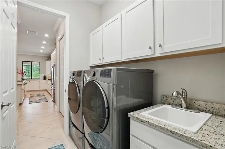 Laundry area featuring cabinet space, washer and clothes dryer, light tile patterned floors, recessed lighting, and crown molding