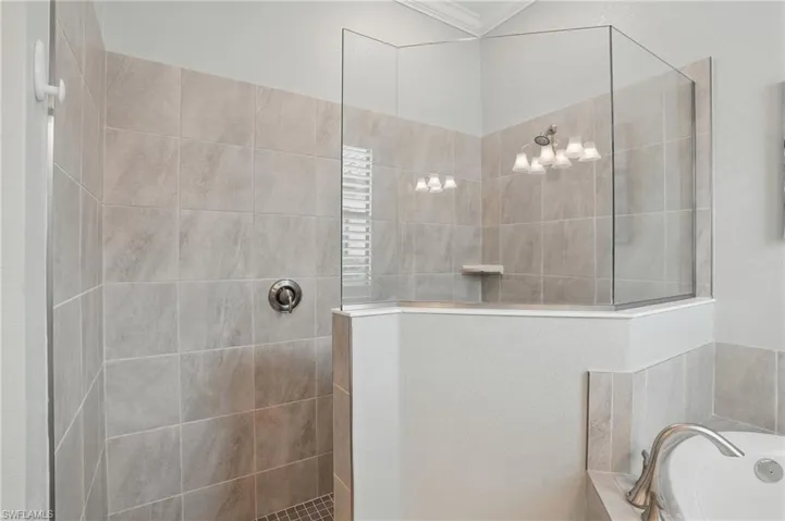 Bathroom with ornamental molding, a bath, and walk in shower