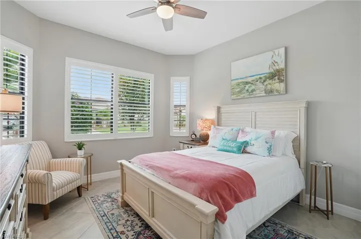 Bedroom with light tile patterned flooring, baseboards, and a ceiling fan