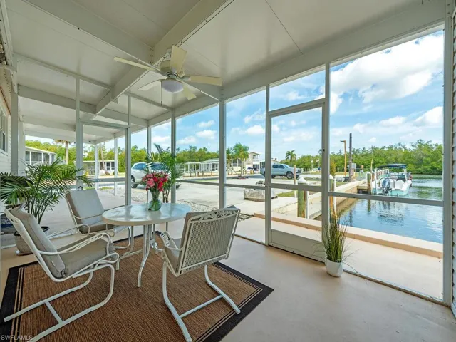 Sunroom / solarium featuring beamed ceiling, a ceiling fan, and a water view