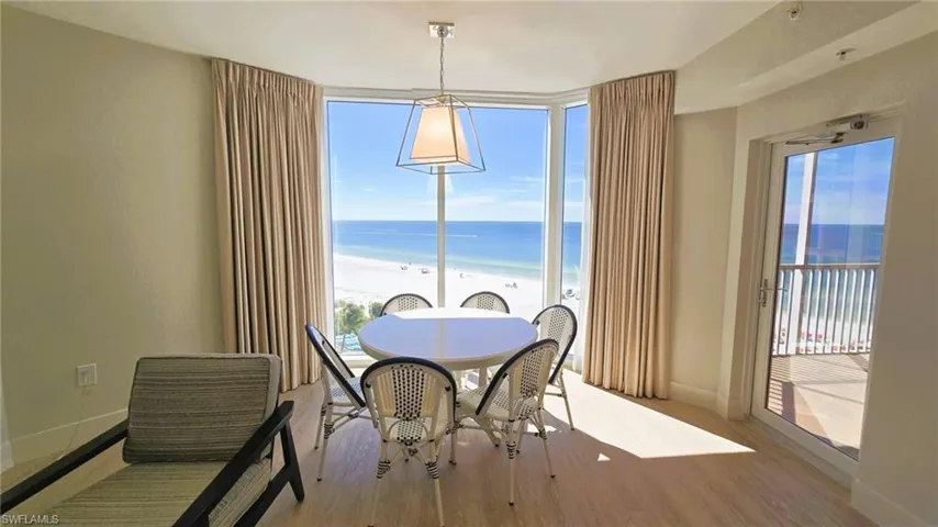 Dining room featuring view of water and beach, wood finished floors, and floor to ceiling windows