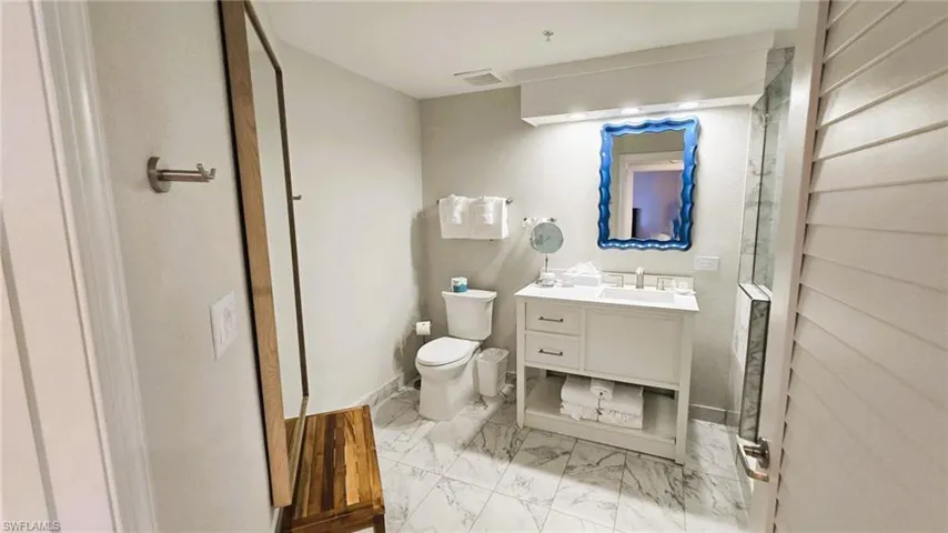 Full bath featuring vanity, light marble finish floors, and a shower