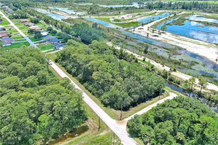 Aerial view of property and surrounding area featuring a nearby body of water and a tree filled landscape