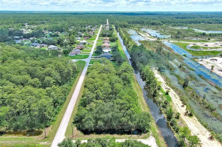 Drone / aerial view of a nearby body of water and a heavily wooded area