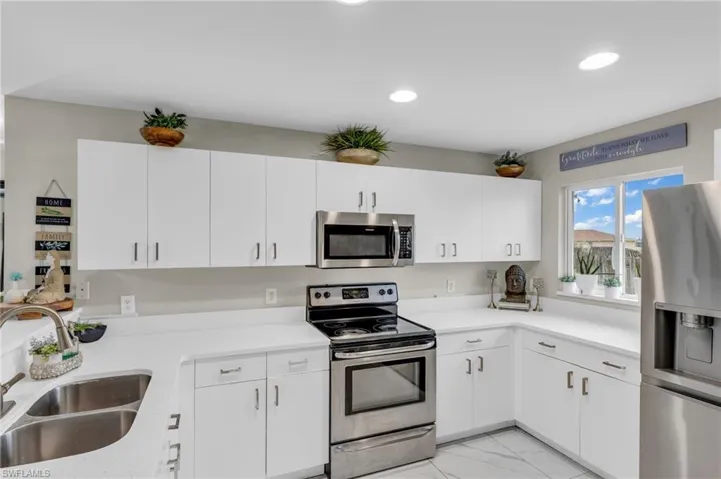 Kitchen featuring light tile patterned floors, white cabinetry, appliances with stainless steel finishes, and sink