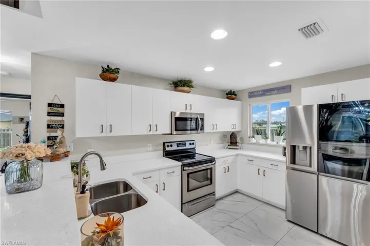 Kitchen featuring sink, stainless steel appliances, light tile patterned floors, and white cabinets