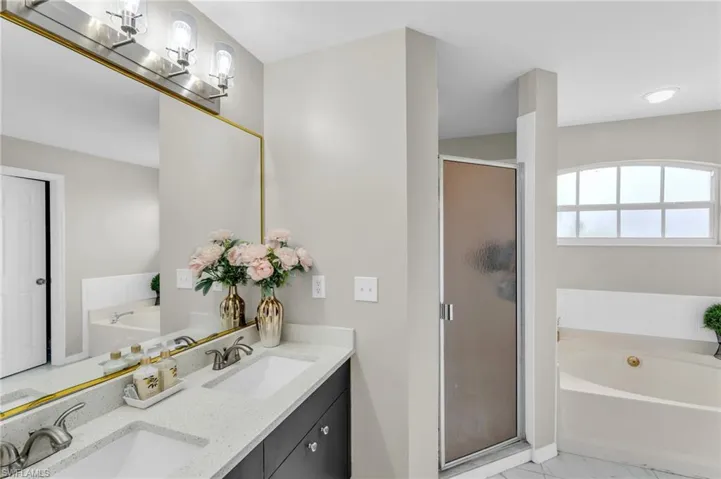 Bathroom with tile patterned flooring, independent shower and bath, and double sink vanity