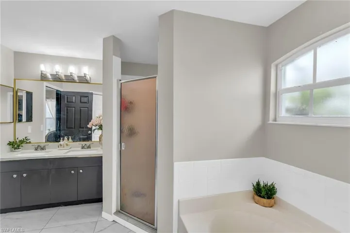 Bathroom with dual vanity, shower with separate bathtub, and tile patterned floors