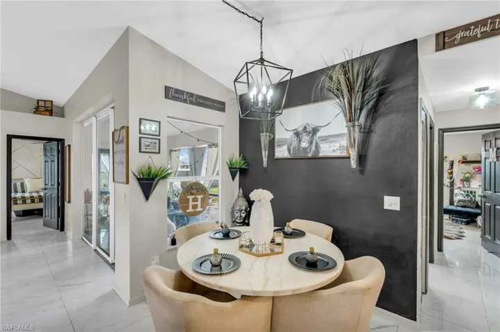 Tiled dining area with lofted ceiling and a notable chandelier