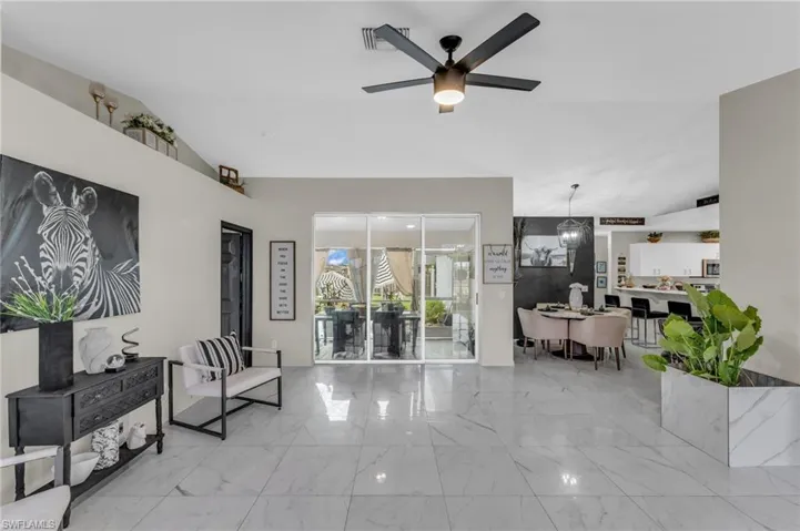 Tiled living room featuring lofted ceiling and ceiling fan