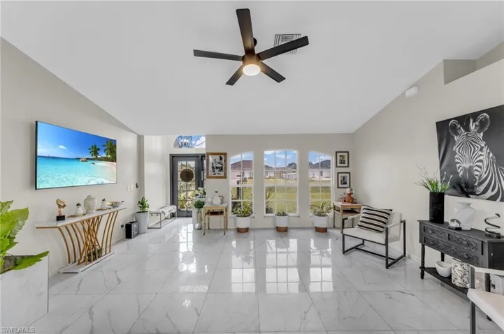 Living room with lofted ceiling, light tile patterned floors, and ceiling fan
