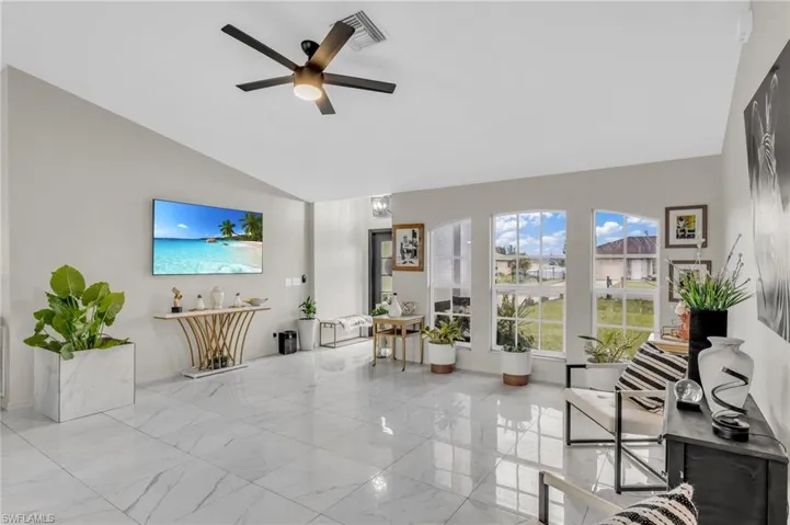 Living room with light tile patterned floors, ceiling fan, and high vaulted ceiling