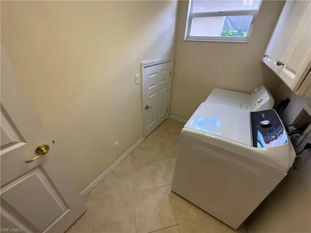 Washroom with washer / clothes dryer, light tile patterned flooring, and cabinets