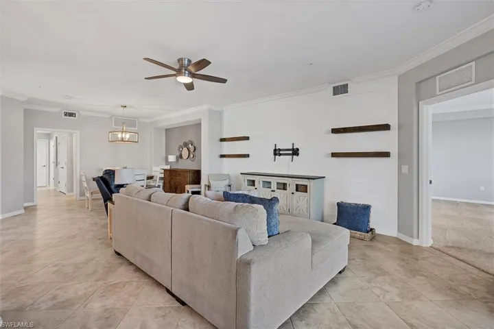 Living area with crown molding, ceiling fan, light tile patterned floors, and hanging lights