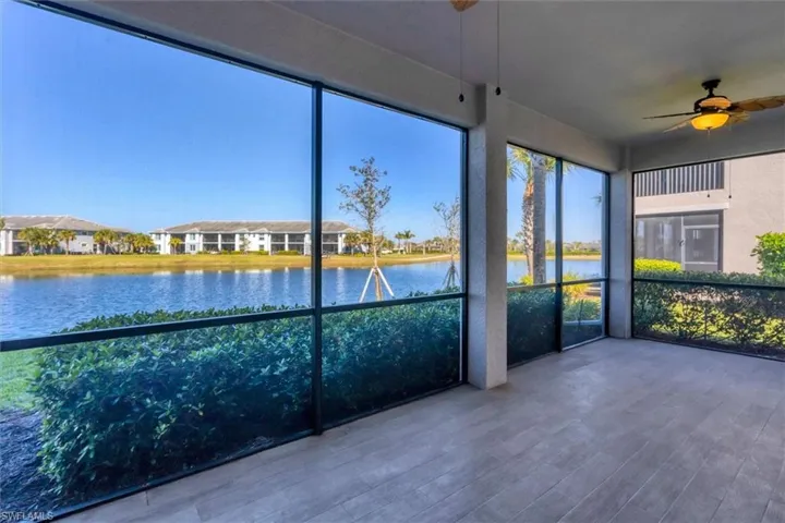 Unfurnished sunroom with a ceiling fan, a water view, and a residential view