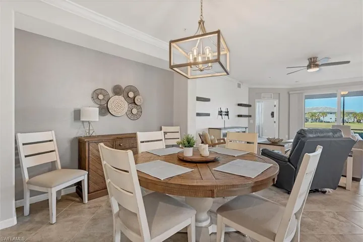 Dining room featuring ornamental molding, ceiling fan, suspended lighting, and light tile patterned floors