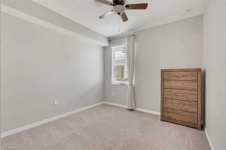 Empty room featuring a ceiling fan and light carpet