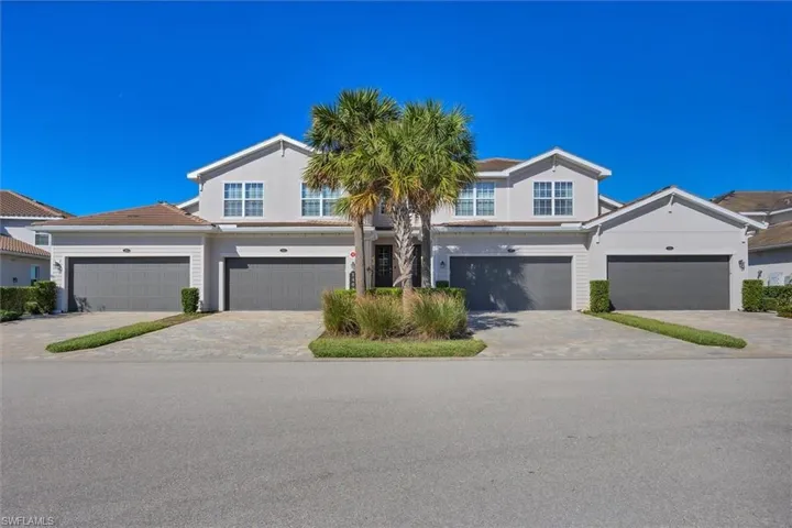 View of front facade with a garage, driveway, and stucco siding