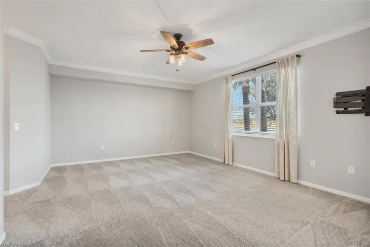 Empty room with crown molding, a ceiling fan, and light colored carpet