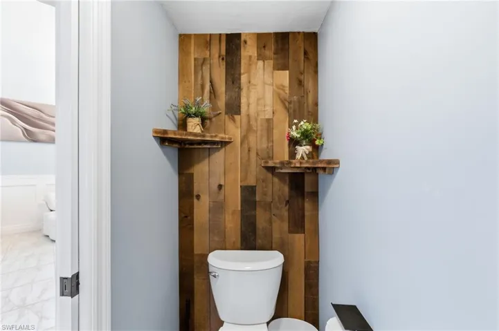 Half bath featuring wood walls and toilet