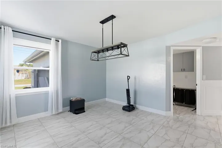 Unfurnished dining area featuring baseboards and light marble finish floors