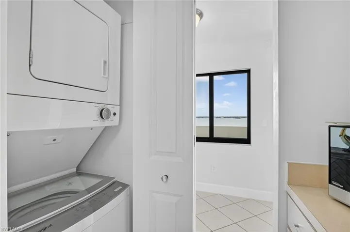 Laundry area featuring light tile patterned floors and stacked washer and dryer