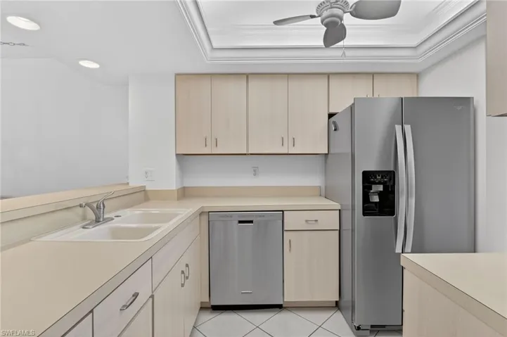 Kitchen with stainless steel appliances, light countertops, ceiling fan, light wood finish cabinets, and light tile patterned flooring