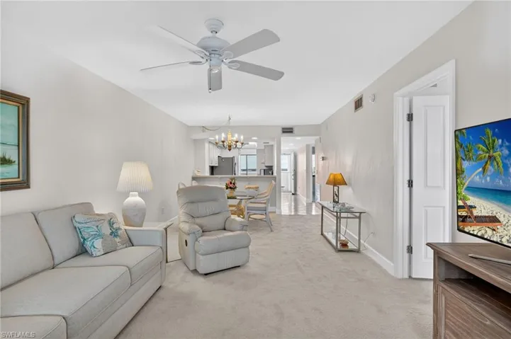 Living room with hanging lights, light carpet, and a ceiling fan